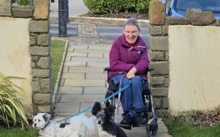 Person in wheelchair with two dogs.